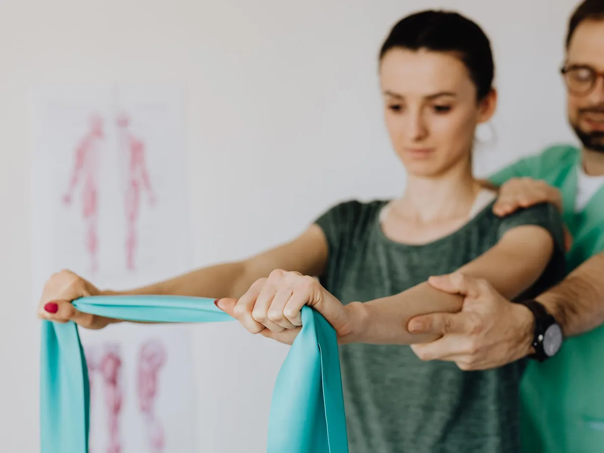 Fisioterapeuta guiando un ejercicio de hombro con banda elástica